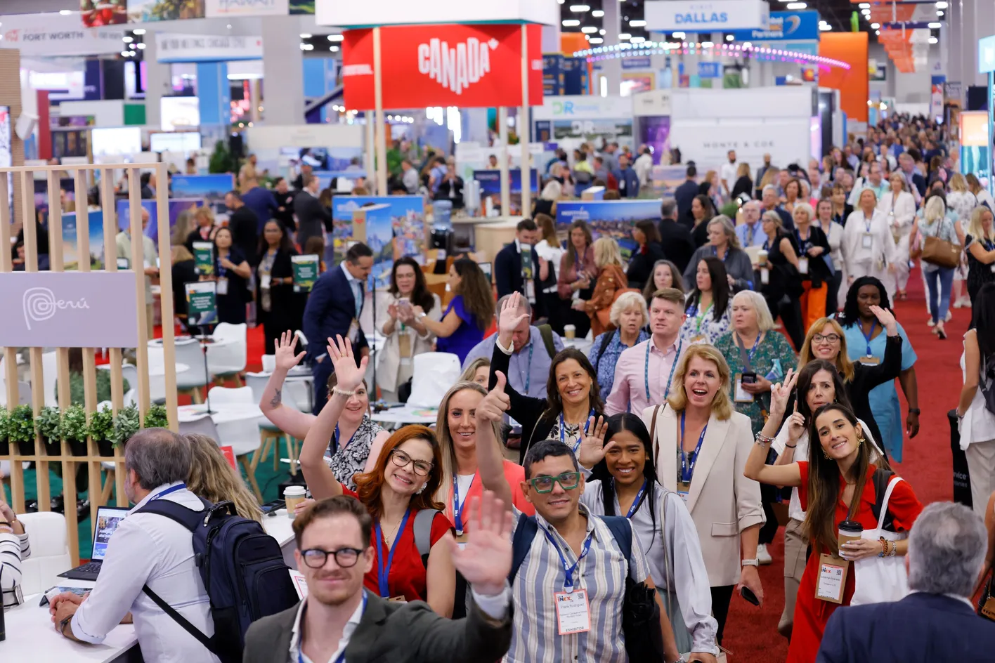 Busy showfloor with people waving at the camera