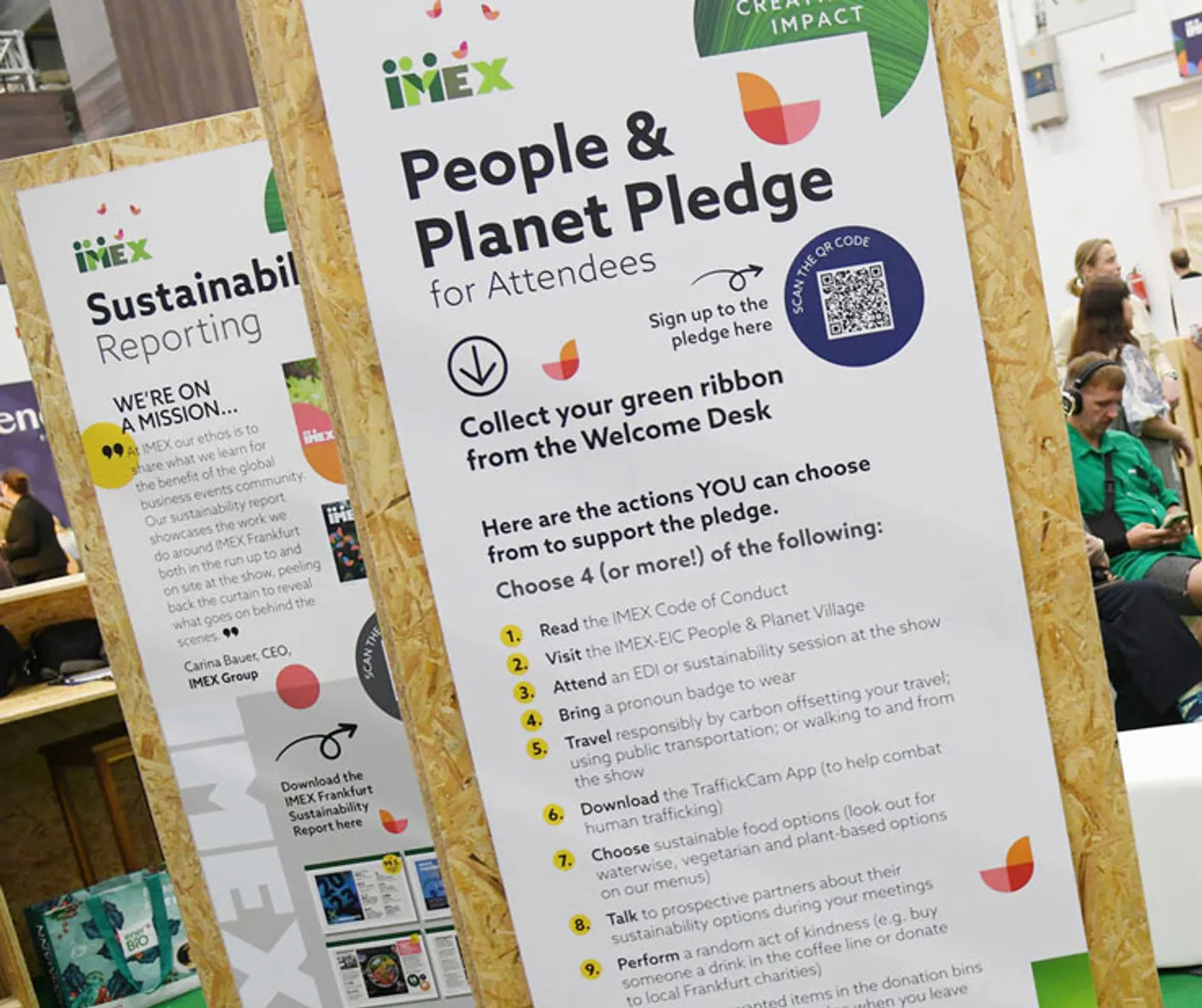 A large, portrait information board explaining the People and Planet Pledge for attendees.