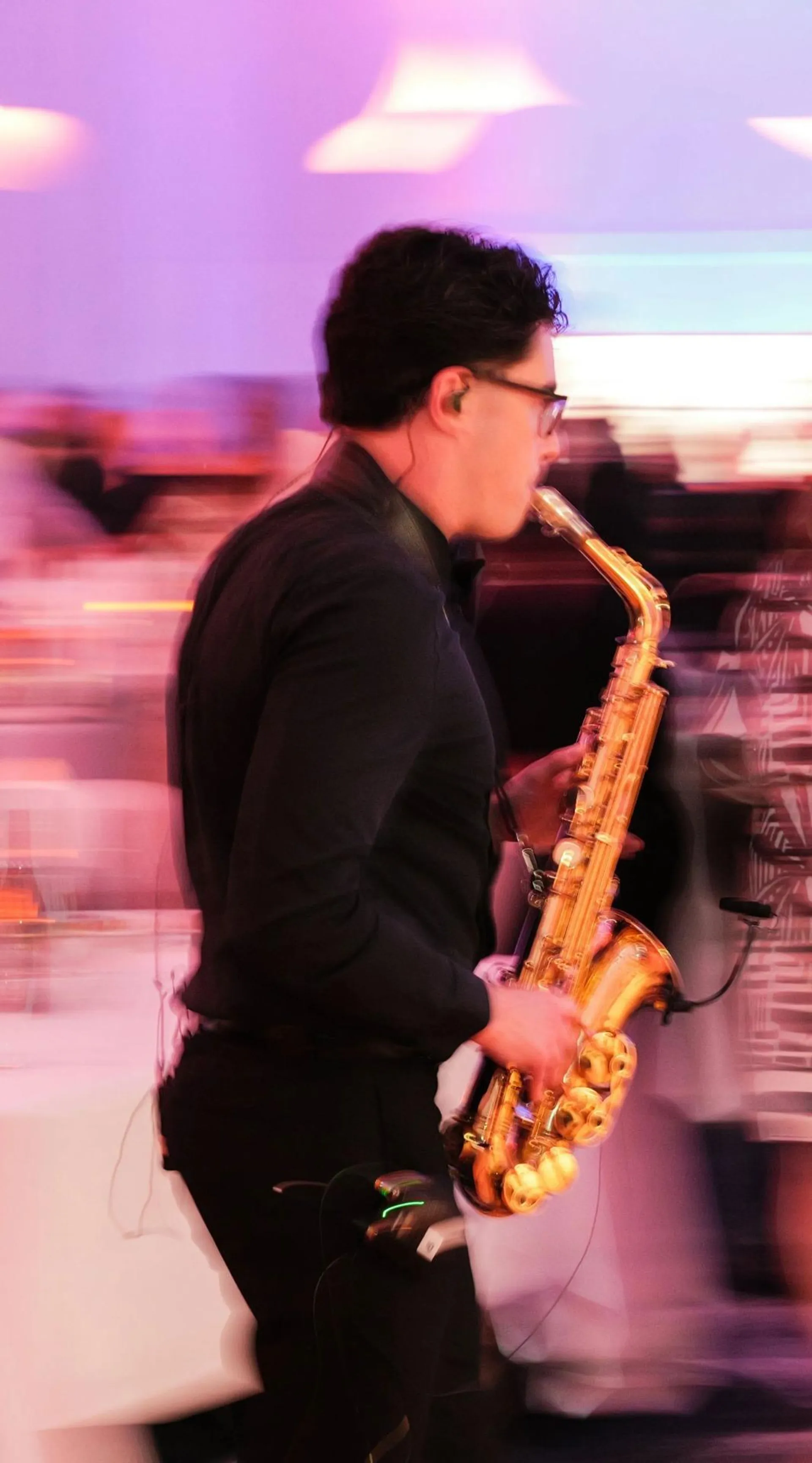 Performer playing a saxophone while walking amongst the tables at the Gala Dinner