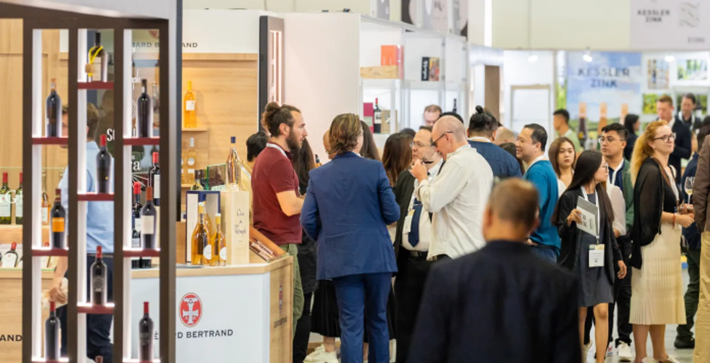 Wine professionals networking and discussing at a Vinexpo Asia exhibitor booth