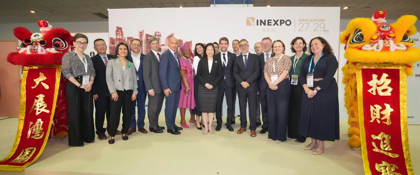 Group of wine professionals posing in front of traditional red Chinese banner at Vinexpo Asia