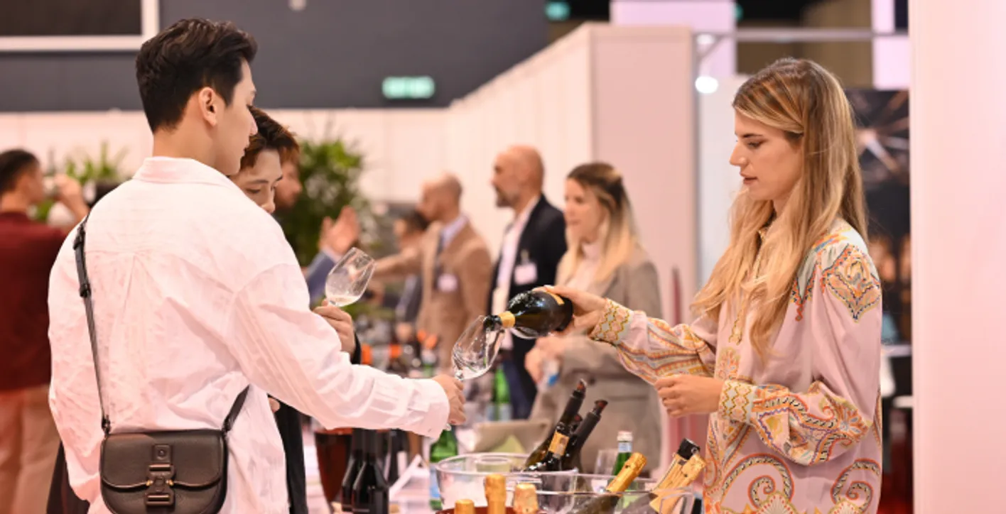 Wine buyer receiving a glass of wine from an exhibitor at Vinexpo Asia