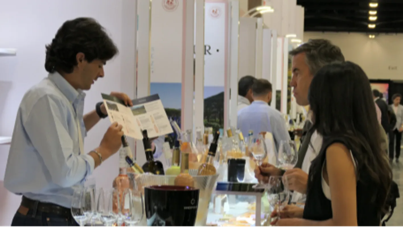 A group of three persons. The exhibitor is introducing his products to visitors.