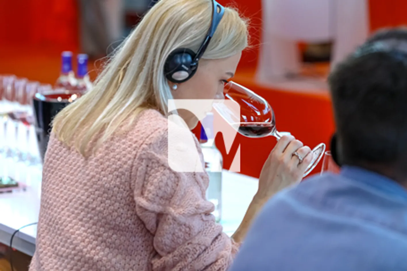 Une femme blonde reniflant son verre de vin durant une session de conférence au salon Wine Paris.