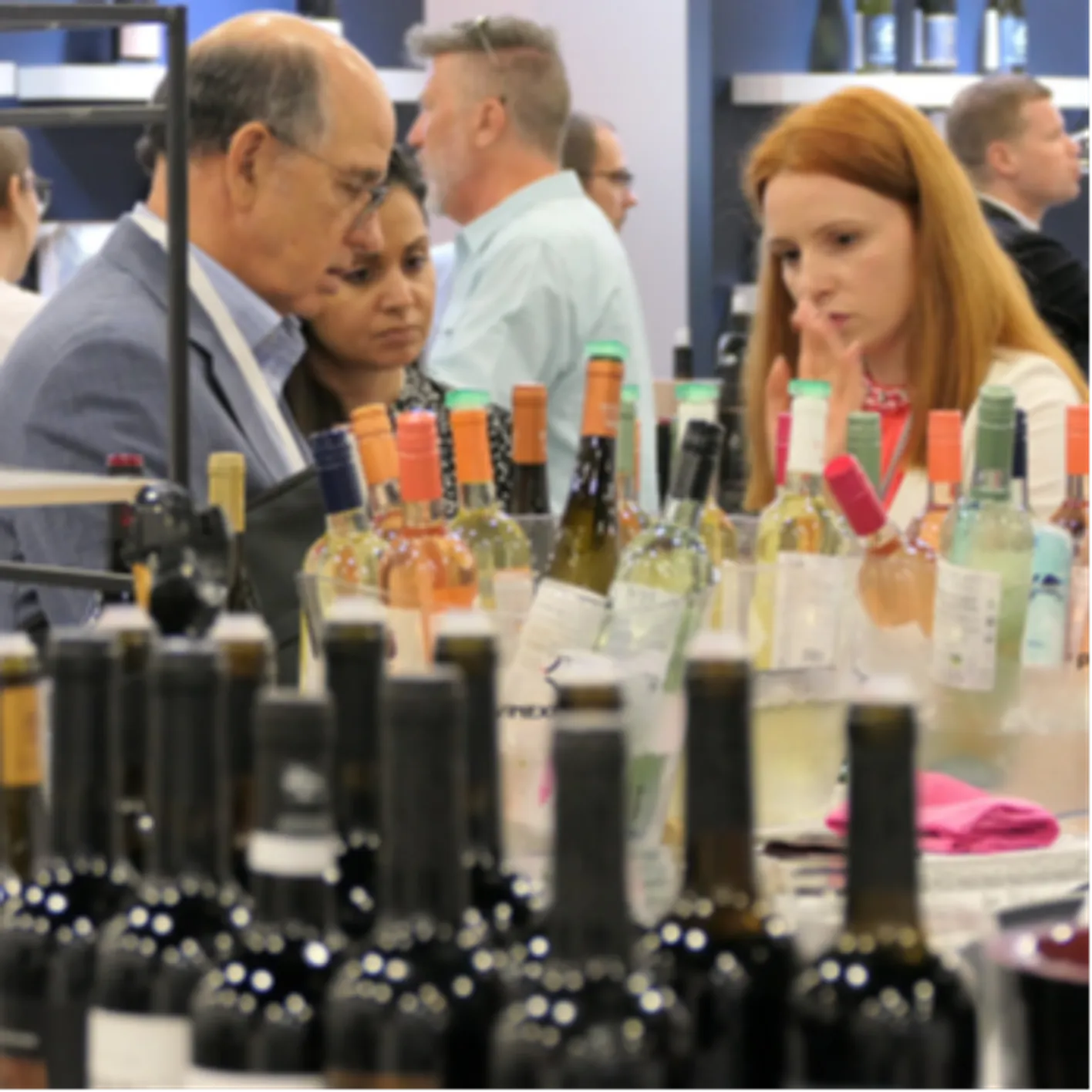 Three person are looking at bottles of wine during Vinexpo Americas.