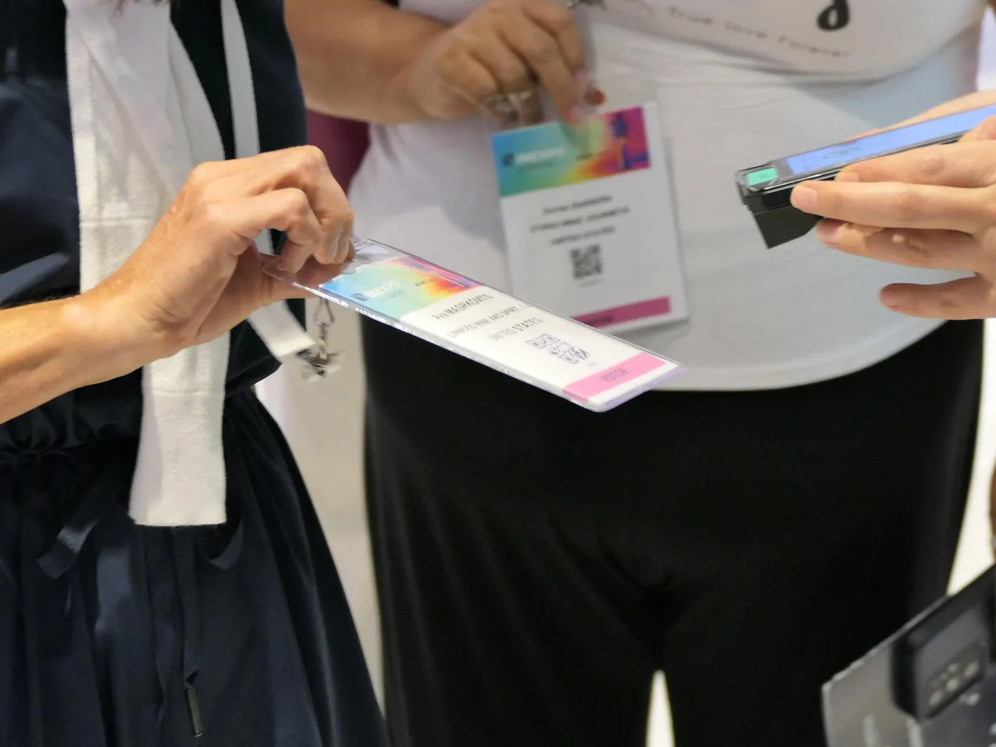 Woman is showing her visitor badge to be scanned at Vinexpo Americas .