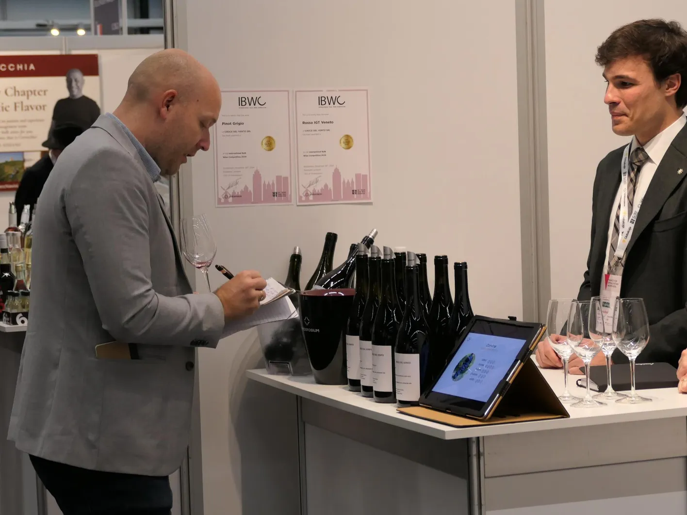One buyer who comes to an exhibitor's booth and holding on his hands a paper notebook.