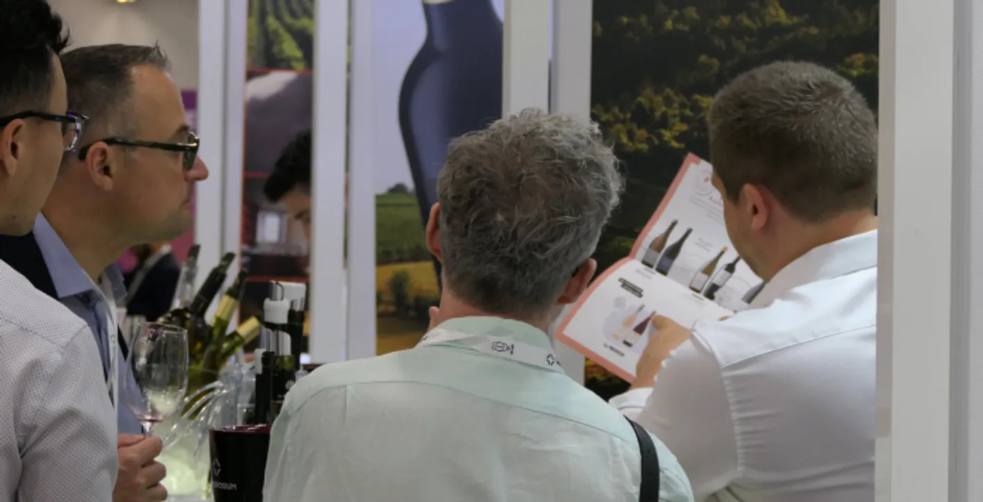 A man who is exhibitor at Vinexpo Americas is pouring wine to someone's glass.