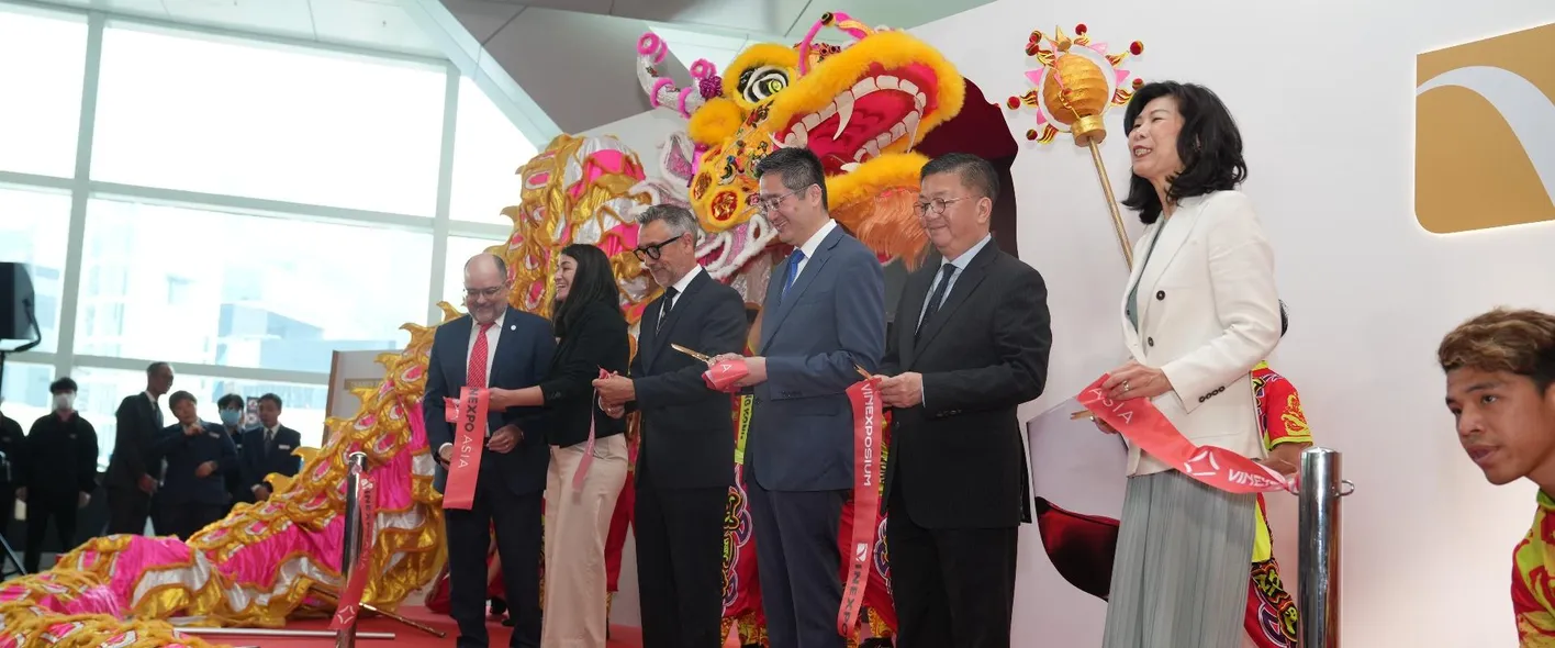 Group of wine professionals posing in front of traditional red Chinese banner at Vinexpo Asia