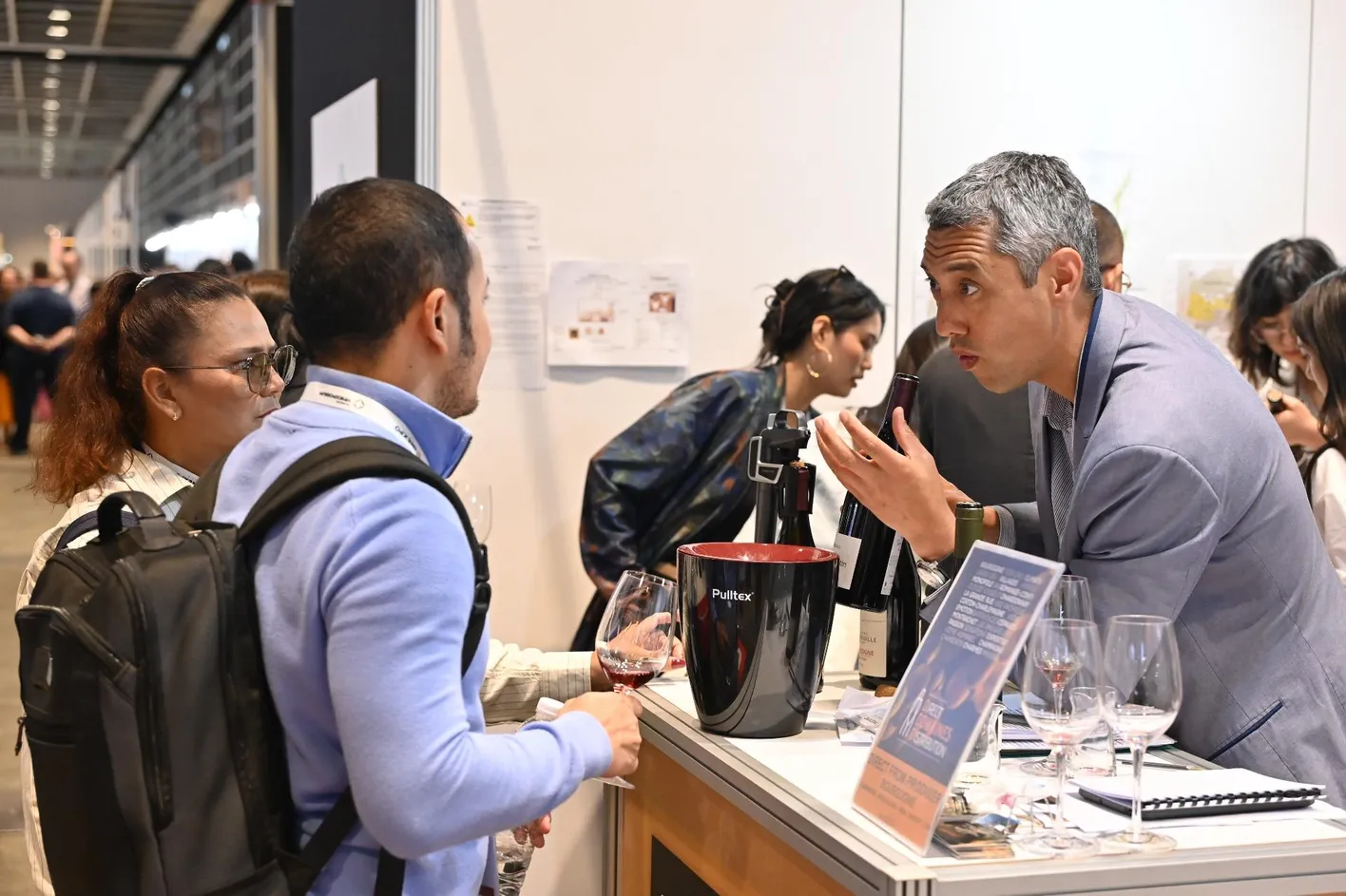 Wine professionals networking and discussing at a Vinexpo Asia exhibitor booth