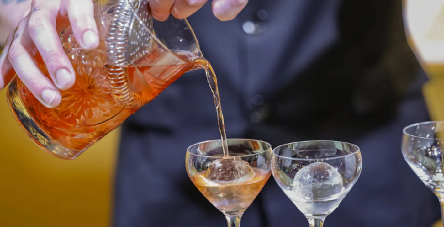 Zoom on a glass while barman is pouring cokcktail