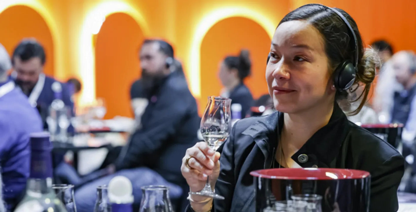 A lady is drinking a spirit glass while listening to the academy session in wine paris