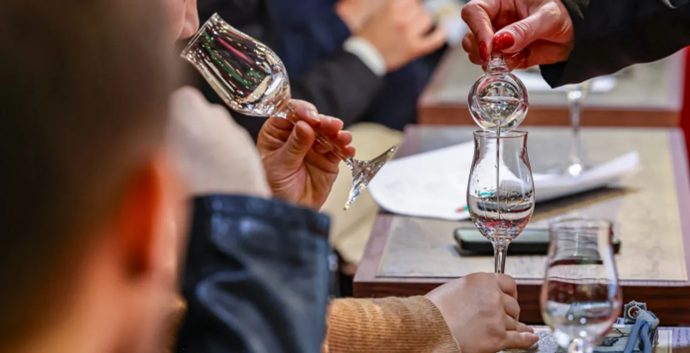 Zoom on hands pouring spirit in a glass