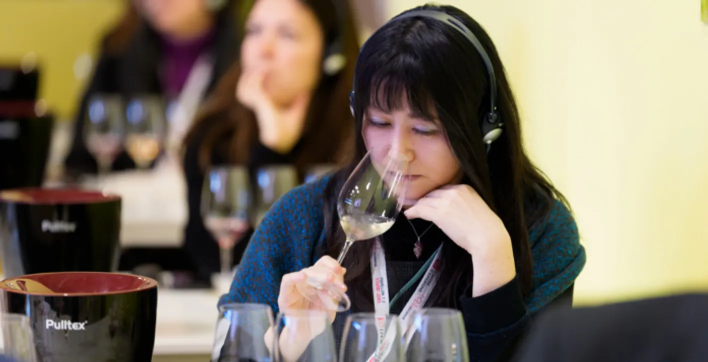 Lady smelling a glass of wine while listening to the academy educationnal session