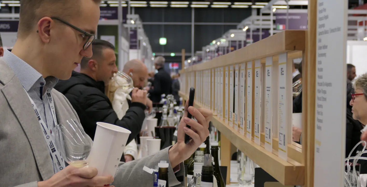man taking a picture with his smartphone of the label of a wine during a degustation