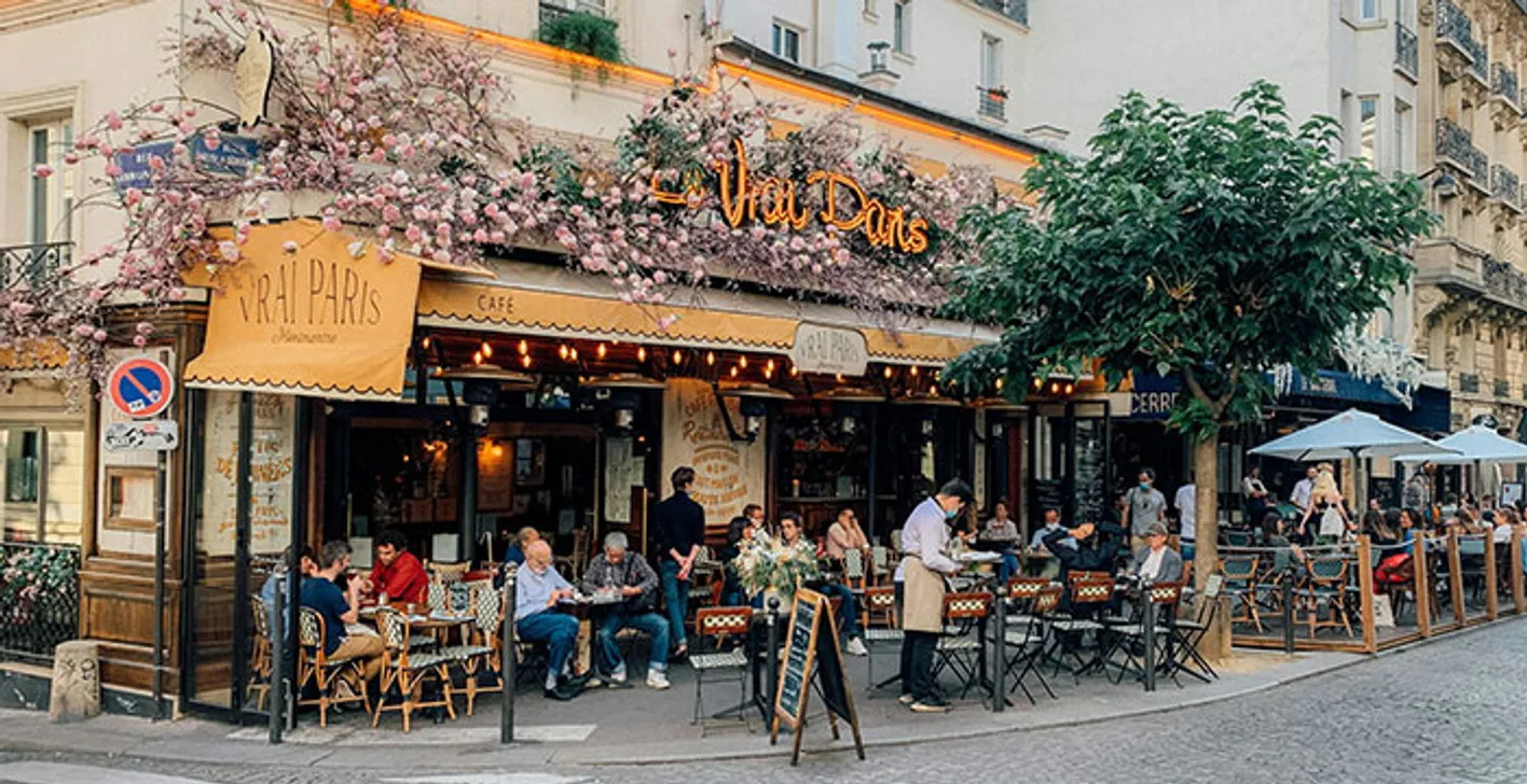 Paris café terrace with people dining on a leafy street